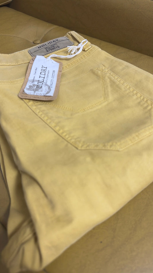 Pantalone Holiday ocra piegato su poltrona gialla con vista sul logo interno