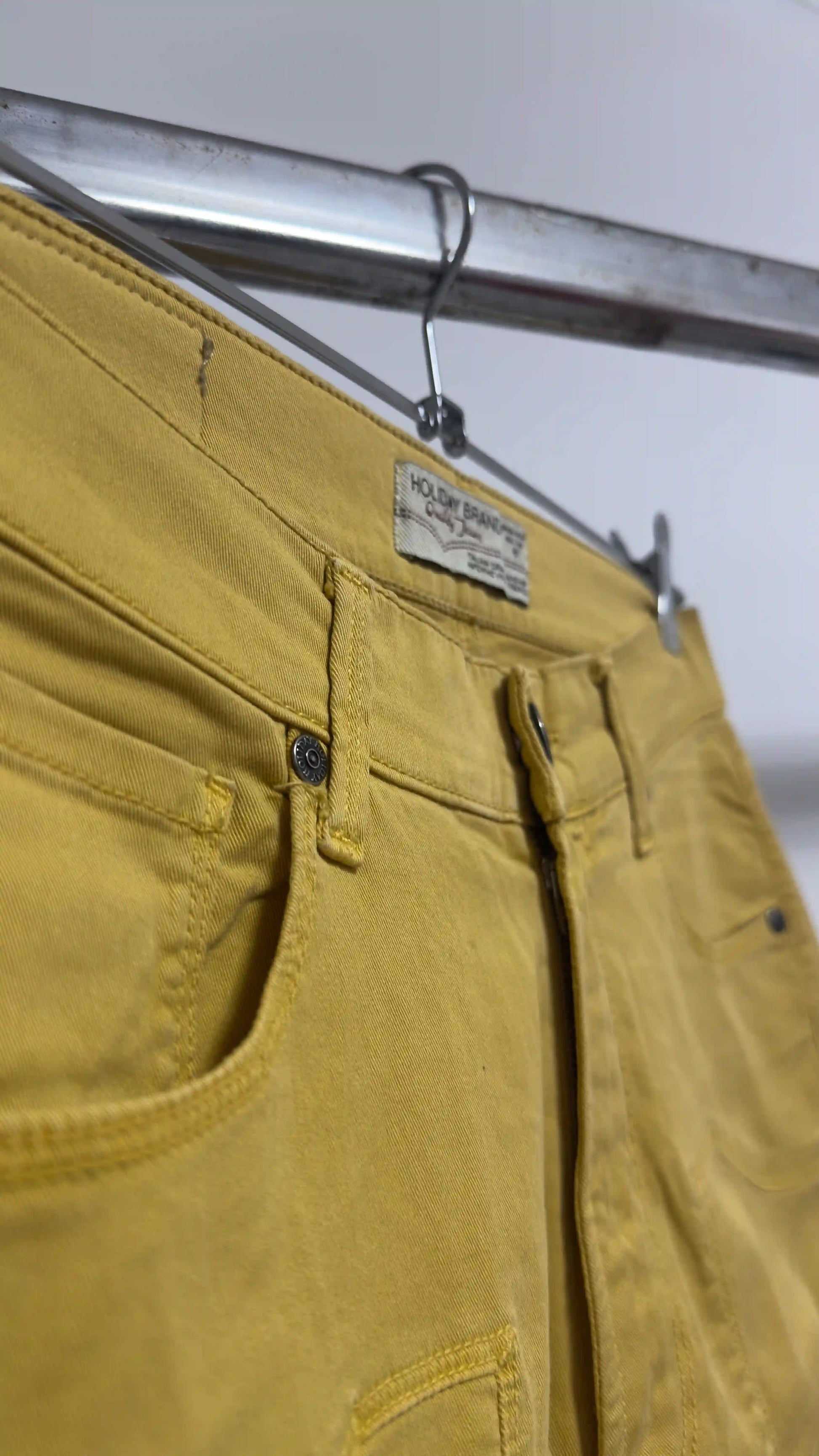 Primo piano cuciture e bottone del pantalone Holiday ocra in cotone elasticizzato