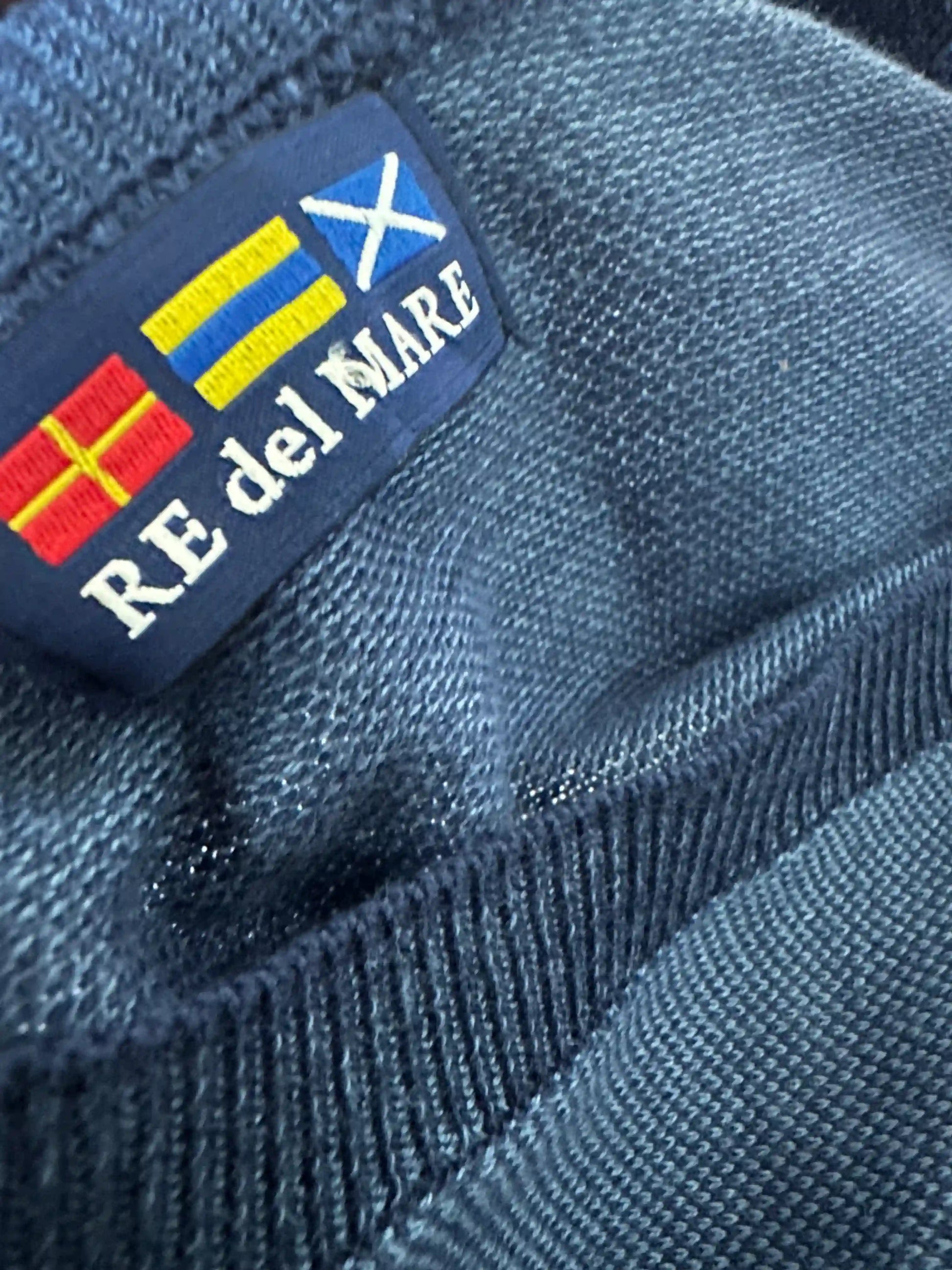 Dettaglio etichetta RE del MARE cucita sul pullover blu avio, con bandiere e logo ricamato